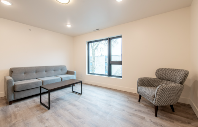 A grey sofa and chair are in a room with a window.